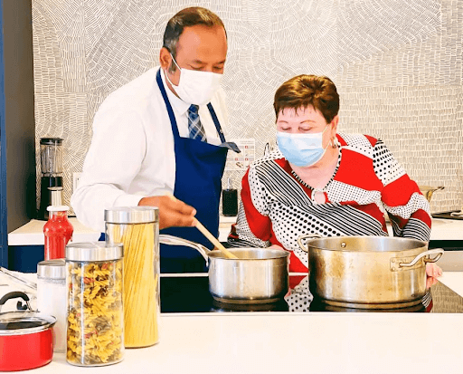 man and woman cooking while wearing masks