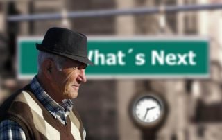 senior citizen in front “what’s next” sign
