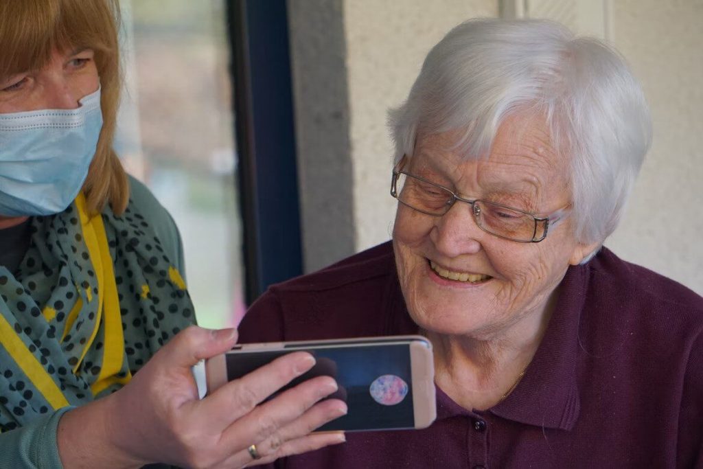 senior and caretaker looking at cell phone